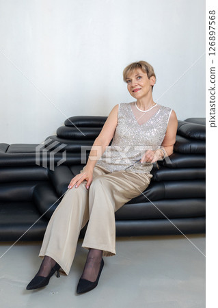 Smiling woman sitting on sofa in bright sunny room. Looking at camera. Vertical photo. High quality photo 126897568