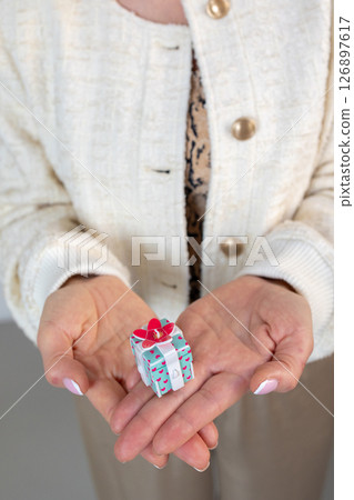 Woman hands holding gift box with red bow, close-up. Vertical photo. High quality photo 126897617