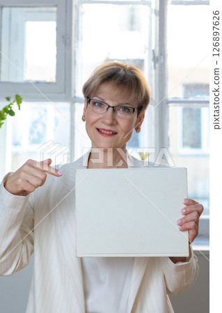 Portrait of emotional woman. Confident woman showing direction with hand on white sheet of paper with space for tex. Looking at camera, banner. Vertical photo. High quality photo Portrait of emotional woman. Confident woman showing direction with hand on white sheet of paper with space for tex. Looking at camera, banner. Vertical photo. High quality photo 126897626