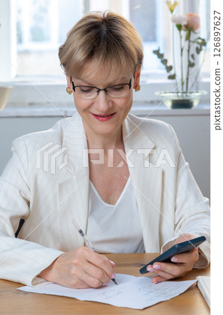 Portrait of business woman. Confident mature woman using mobile phone and typing. Vertical photo. High quality photo Portrait of business woman. Confident mature woman using mobile phone and typing. Vertical photo. High quality photo 126897627