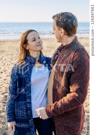Loving couple walks on beach along sea on sunny autumn day. Weekend and lifestyle concept. Vertical photo. High quality photo 126897661