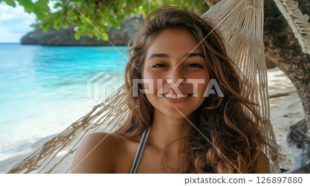 Smiling woman relaxing in hammock by tropical beach 126897880