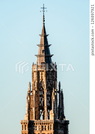 A majestic view of the Toledo Cathedral's intricate bell tower piercing the clear, blue Spanish sky. 126897921