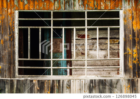 Old broken window with bars showing peeling paint and decay 126898045
