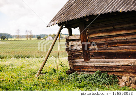 Old wooden barn collapsing in green field near fence Old wooden barn collapsing in green field near fence 126898058
