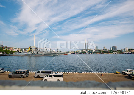 Russian naval vessels mooring near golden bridge, vladivostok waterfront, bright sunlight illuminating maritime scene 126898185