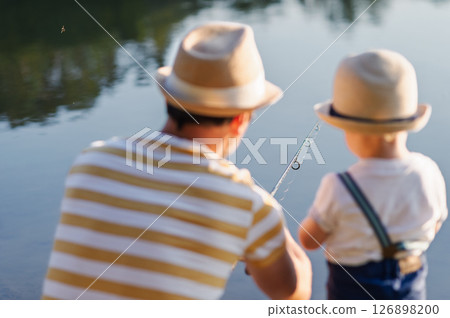 Dad teaching his little boy how to fish by the lake 126898200