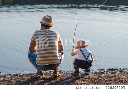 Dad teaching his little boy how to fish by the lake Dad teaching his little boy how to fish by the lake 126898205