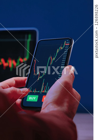 Close up, trader hands holding smartphone with trading application 126898226