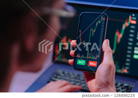 crypto trader analyzing live cryptocurrency and stock charts on smartphone crypto trader analyzing live cryptocurrency and stock charts on smartphone 126898228