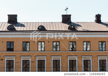 A symmetrical facade of a historic light orange building in Helsinki under a clear sky. 126898265