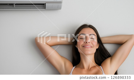 Relaxed young caucasian female enjoying cool air from air conditioner 126898333