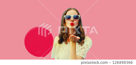 Portrait of beautiful young woman blowing her lips sweet air kiss with balloon on pink background Portrait of beautiful young woman blowing her lips sweet air kiss with balloon on pink background 126898366