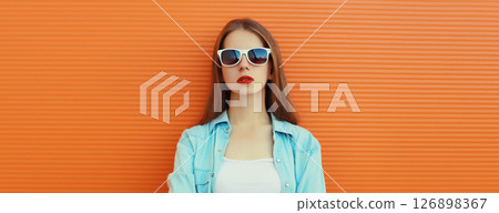 Portrait of modern stylish young woman in glasses, casual clothing posing on orange background Portrait of modern stylish young woman in glasses, casual clothing posing on orange background 126898367