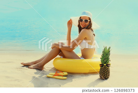 Summer vacation, tourism, happy woman with swimming inflatable ring sitting on the beach on sea Summer vacation, tourism, happy woman with swimming inflatable ring sitting on the beach on sea 126898373