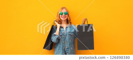Shopping day, stylish beautiful happy smiling young woman with black shopping bags on yellow wall Shopping day, stylish beautiful happy smiling young woman with black shopping bags on yellow wall 126898380