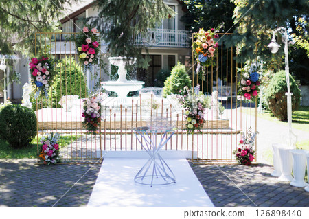 Wedding arch decorated with colorful flowers standing outdoor 126898440