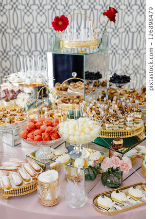 Catering service presenting delicious desserts and fruits on a table Catering service presenting delicious desserts and fruits on a table 126898479