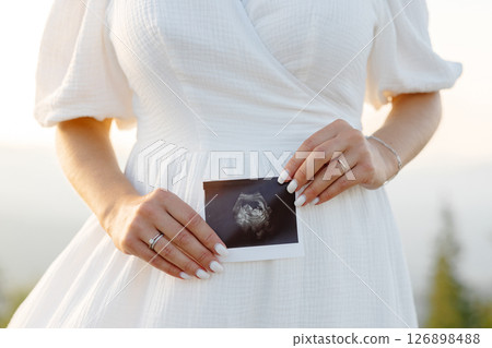 Pregnant woman holding ultrasound scan photo of baby, motherhood and pregnancy concept 126898488