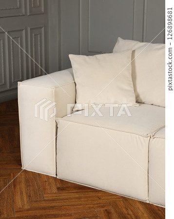 A modern white sofa with soft cushions enhances an elegant interior, creating a stylish ambiance A modern white sofa with soft cushions enhances an elegant interior, creating a stylish ambiance 126898681