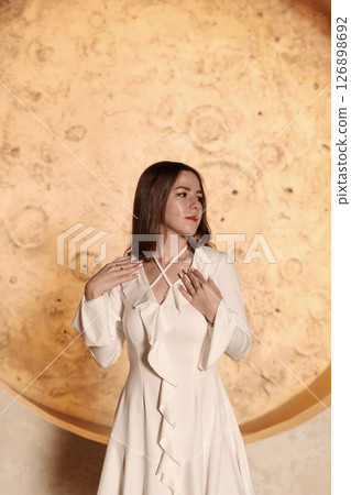 An Elegant Woman Gracefully Posing in a Beautiful White Dress Against a Celestial Background An Elegant Woman Gracefully Posing in a Beautiful White Dress Against a Celestial Background 126898692