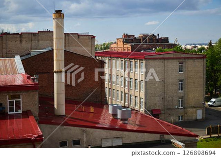 A picturesque urban rooftop view showcasing vibrant red roofs along with a chimney structure A picturesque urban rooftop view showcasing vibrant red roofs along with a chimney structure 126898694