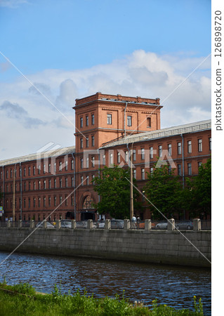 A Beautiful Historic Red Brick Building Situated Alongside the Riverbank in a Scenic Urban Landscape A Beautiful Historic Red Brick Building Situated Alongside the Riverbank in a Scenic Urban Landscape 126898720
