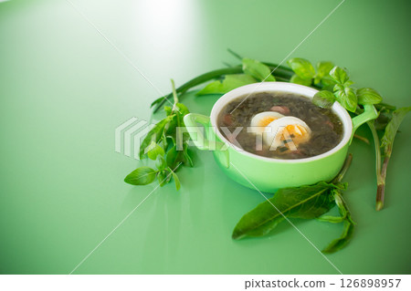 Appetizing spring sorrel borscht isolated on a green background Appetizing spring sorrel borscht isolated on a green background 126898957