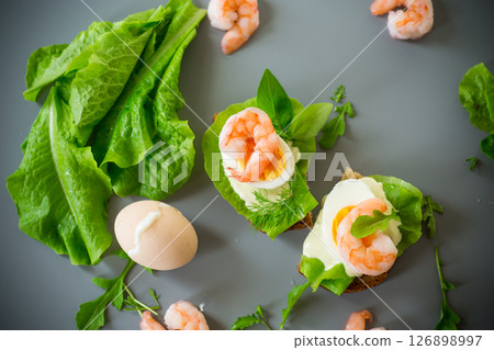 Sandwich with egg, lettuce and shrimp isolated on gray background Sandwich with egg, lettuce and shrimp isolated on gray background 126898997