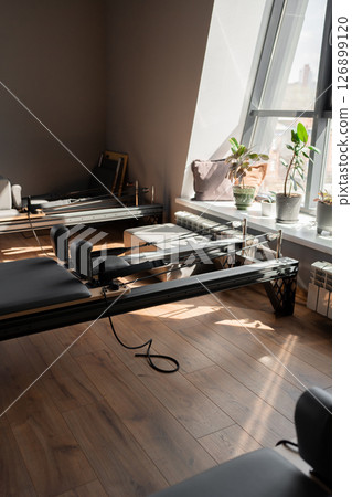 Modern Pilates studio with reformer beds bright, spacious windows for exercise and wellbeing 126899120