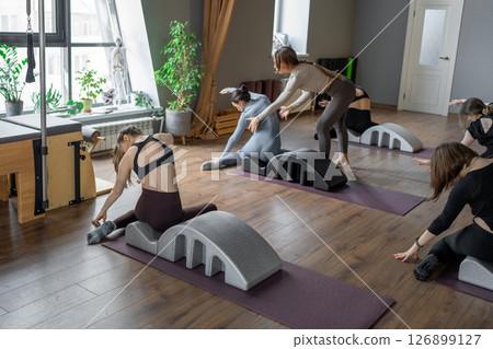 Woman doing mermaid exercise on back spine corrector. Reformer pilates studio machine for fitness workouts in gym. Fit, healthy and strong authentical body. Fitness concept. Woman doing mermaid exercise on back spine corrector. Reformer pilates studio machine for fitness workouts in gym. Fit, healthy and strong authentical body. Fitness concept. 126899127