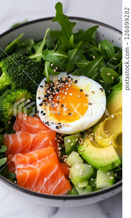 A nutritious breakfast bowl features slices of salmon, creamy avocado, a soft-boiled egg, and vibrant greens like arugula and broccoli, presented in a cozy kitchen ambiance A nutritious breakfast bowl features slices of salmon, creamy avocado, a soft-boiled egg, and vibrant greens like arugula and broccoli, presented in a cozy kitchen ambiance 126899282