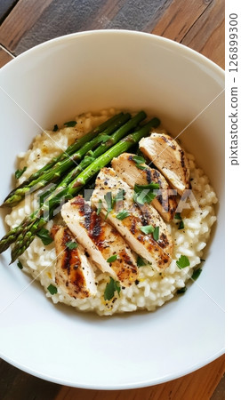 A delectable risotto, rich and creamy, features succulent grilled chicken slices and tender asparagus, served in a cozy Italian kitchen, inviting a warm culinary experience A delectable risotto, rich and creamy, features succulent grilled chicken slices and tender asparagus, served in a cozy Italian kitchen, inviting a warm culinary experience 126899300