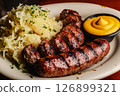 Savory bratwurst grilled to perfection alongside fresh sauerkraut and a side of mustard, served in a warm and inviting atmosphere ideal for a hearty meal 126899321