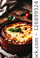 A traditional Italian lasagna is being cooked in a rustic oven, showcasing layers of meat, cheese, and sauce bubbling with flavor, creating an inviting aroma in the kitchen 126899324