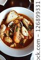Traditional bouillabaisse seafood stew served in a rustic bowl with fresh herbs and crusty bread at a cozy French restaurant 126899331