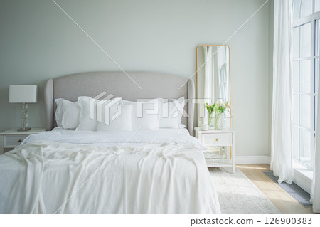 Stylish loft bedroom interior. Spacious design apartment with light walls large windows big bed. Clean modern decoration with elegant furniture in minimalist Scandinavian style Stylish loft bedroom interior. Spacious design apartment with light walls large windows big bed. Clean modern decoration with elegant furniture in minimalist Scandinavian style 126900383