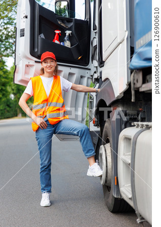 Portrait young adult happy smiling woman climbing cabin heavy truck driver cargo vehicle. Female person girl professional job career working driving freight engine lorry. Logistics industry Portrait young adult happy smiling woman climbing cabin heavy truck driver cargo vehicle. Female person girl professional job career working driving freight engine lorry. Logistics industry 126900610