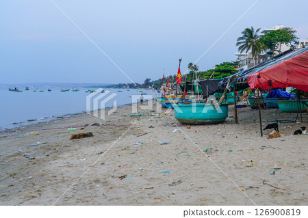 Fishing boats and shelters along a littered beach in Vietnam during a quiet,early morning by the sea 126900819