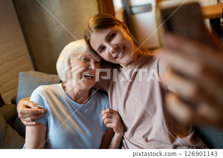 Young female volunteer and elderly woman making selfie and looking enjoyed 126901143