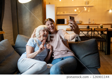 Young female volunteer and elderly woman making selfie and looking enjoyed Young female volunteer and elderly woman making selfie and looking enjoyed 126901144