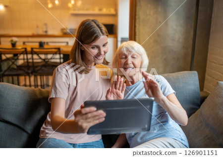 Elderly woman and young volunteer watching something on the laptop together Elderly woman and young volunteer watching something on the laptop together 126901151
