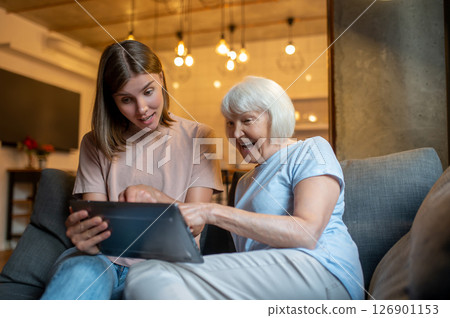 Elderly woman and young volunteer watching something on the laptop together 126901153