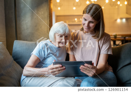 Elderly woman and young volunteer watching something on the laptop together 126901154