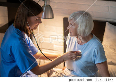 Doctor examining elderly patient and looking concentrated Doctor examining elderly patient and looking concentrated 126901167
