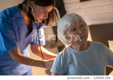 Doctor examining elderly patient and looking concentrated 126901169
