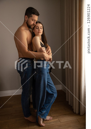 Man in jeans hugging woman their faces close in tender embrace in home setting Man in jeans hugging woman their faces close in tender embrace in home setting 126901224