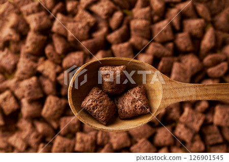 wooden spoon of delicious chocolate pillows above tasty chocolate corn balls as background. Top view. 126901545