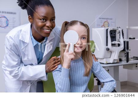 African american optometrist working with a small patient and looking friendly 126901644