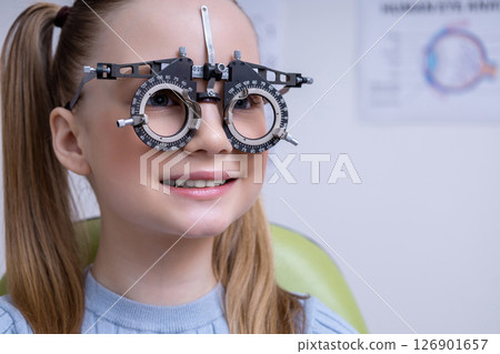 Fair-haired school age girl having an optometry test in clinic 126901657